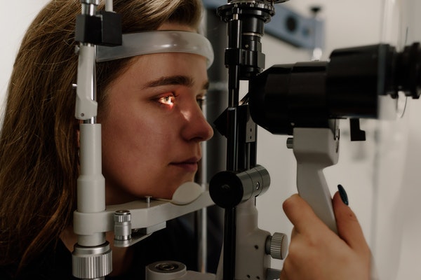 Autorefractor machine and a woman placing her heard in it for eye checkup